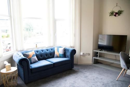 a blue couch in a living room with a tv at Cosy Stays in Redcar