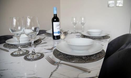 a table with glasses and plates and a bottle of wine at Cosy Stays in Redcar