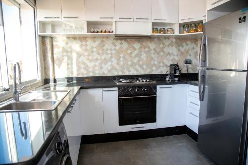 een keuken met witte kasten en een roestvrijstalen koelkast bij Pure apartments in Taroudant