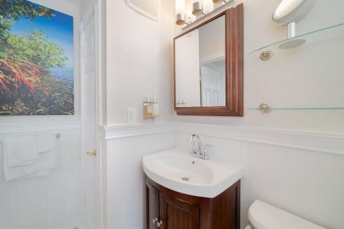 a white bathroom with a sink and a mirror at The Savannah - Perfect Couple Getaway! in West Palm Beach