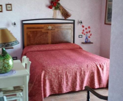 a bedroom with a red bed and a table with a lamp at Agriturismo Il Maggio in Manciano