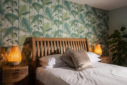 1 dormitorio con 1 cama con 2 lámparas y papel pintado en The Crescent Turner Hotel en Whitstable