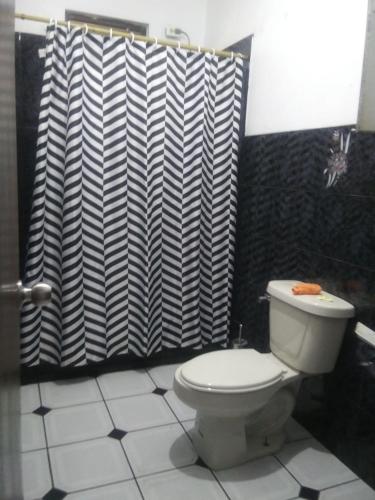 a bathroom with a toilet and a black and white shower curtain at Brisas de Borinquen in Aguadilla