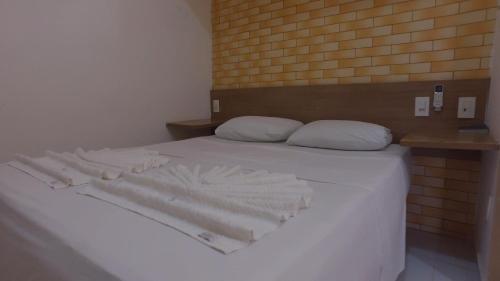 a bed with white sheets and pillows on it at Pousada Caribe Sul in Barra do Cunhau