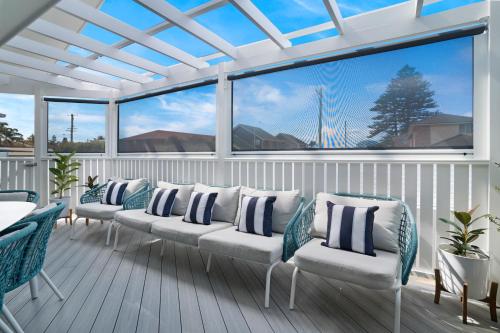 a porch with white chairs and a large window at Entire Residential Home - Lake Illawarra And Beachside Home Sleeps 12 in Lake Illawarra