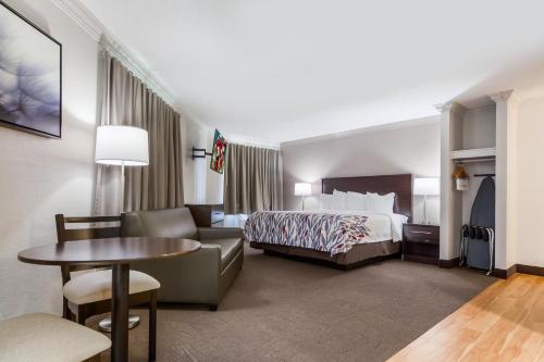 a hotel room with a bed and a table at Red Roof Inn & Suites Omaha - Council Bluffs in Council Bluffs