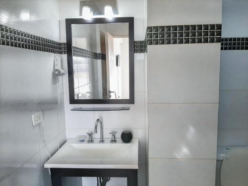 a white bathroom with a sink and a mirror at Costa Mar in Puerto Madryn