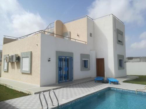 a house with a swimming pool in front of it at Belle Villa Proche Marina in Houmt Souk