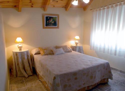 a bedroom with a large bed with two lamps on tables at BAHIA DEL LAGO in Villa Carlos Paz
