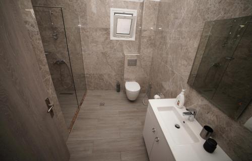 a bathroom with a sink and a shower and a toilet at Apartments Serxhio in Sarandë