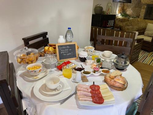 a table with a white table cloth with food on it at O Cantinho da Ana in Sortelha