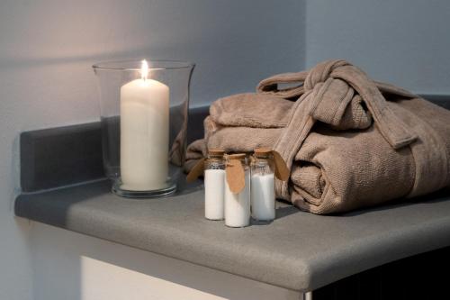 a candle and towels on a table with a towel at F1RST Suite Apartment & SPA in Florence