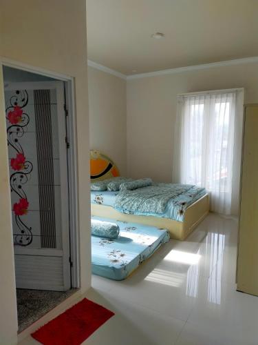a bedroom with two beds and a window at Villa keluarga Pandansari in Malang