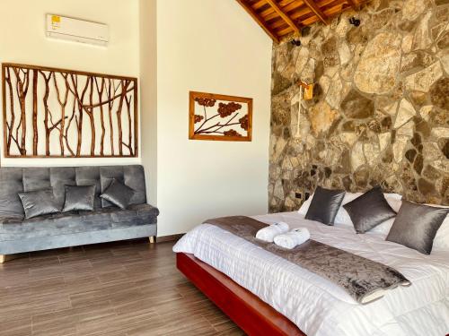 a bedroom with a bed and a stone wall at Hotel Campestre Palmas del Zamorano in San Gil