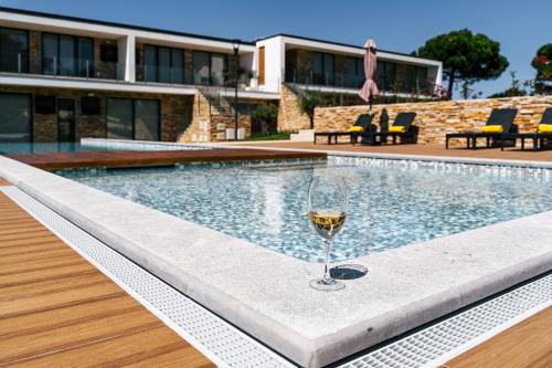 a glass of wine sitting next to a swimming pool at ALTO DA GARÇA - PRIME VILLAS & SPA in Nadadouro