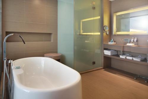 uma casa de banho com uma banheira e um chuveiro em vidro. em Noble Resort Hotel Melaka em Malaca