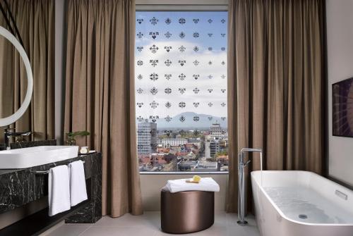 a bathroom with a tub and a window with a view at InterContinental - Ljubljana by IHG in Ljubljana