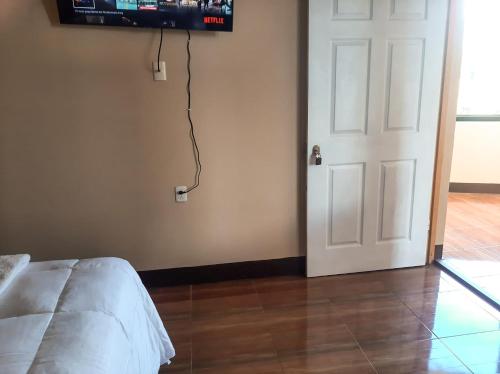 1 dormitorio con puerta y TV en la pared en Millennium Apartment, en San Pedro La Laguna