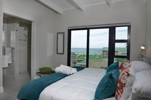 a bedroom with a bed with a view of the ocean at The Whale and Waddler in Kleinmond