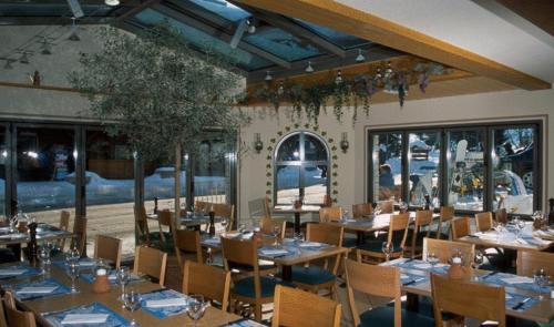 un comedor con mesas, sillas y ventanas en Hotel Steinbock Grindelwald, en Grindelwald