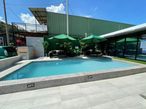 a swimming pool with two green umbrellas in front of a building at The Sky Inn in Kuantan