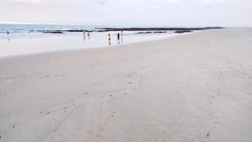 a group of people walking on the beach at Samant Beach Resort in Malvan