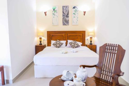 a bedroom with a bed and a chair and a table at ilamparuma Hotel in Weligama