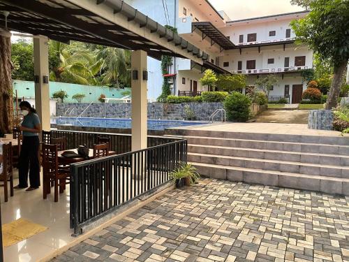 a person sitting at a table in a patio with stairs at ilamparuma Hotel in Weligama
