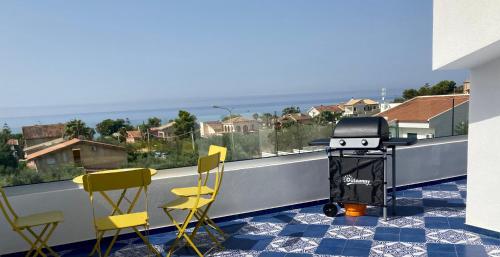 a balcony with yellow chairs and a grill on a balcony at Le case di Fiò in Sciacca