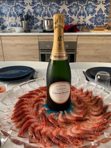 a bottle of champagne next to a plate of shrimp at Le case di Fiò in Sciacca