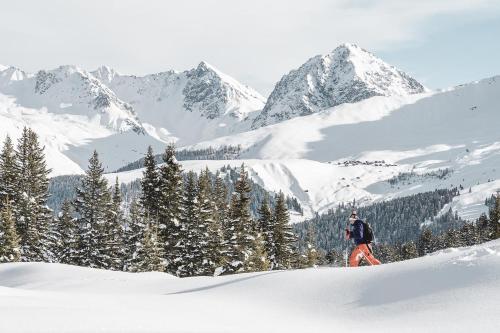 a person on skis in the snow with mountains in the background at Hotel Alpensonne - Panoramazimmer & Restaurant in Arosa
