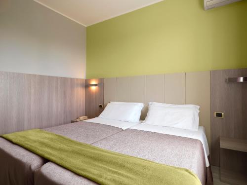 a bedroom with a large bed with a green blanket on it at Hotel San Francesco in Borgomanero