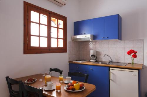 a kitchen with blue cabinets and a table with fruit on it at Flisvos Rooms in Plakias