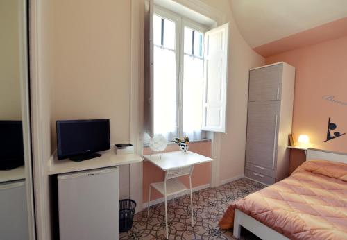 a bedroom with a bed and a desk with a television at *1*7*4* Via Roma in Palermo