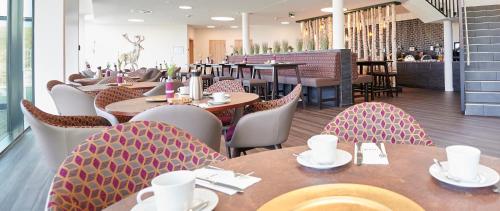 Hotel FÜNF10 في Netphen: مطعم بطاولات وكراسي خشبية ومطعم به