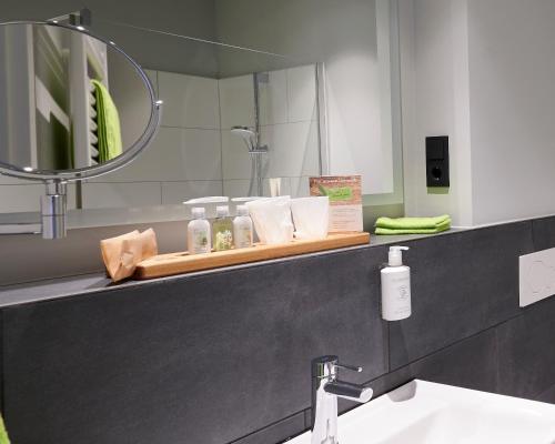 ein Bad mit einem Waschbecken und einem Spiegel in der Unterkunft Hotel FÜNF10 in Netphen