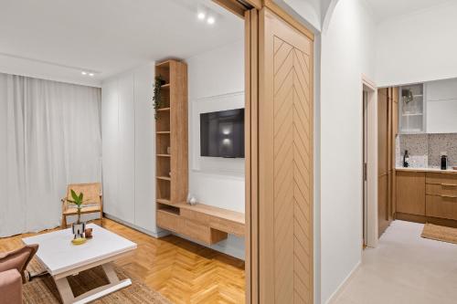 Ein Zimmer mit einer Tür, die zu einem Wohnzimmer mit einem TV führt. in der Unterkunft Little Athens in Athen