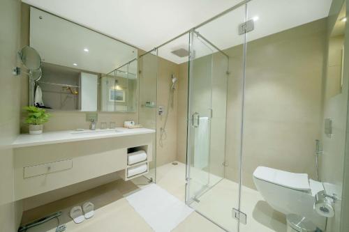 a bathroom with a shower and a sink and a toilet at Jade Suites - Luxury Boutique Hotel in Vijayawāda