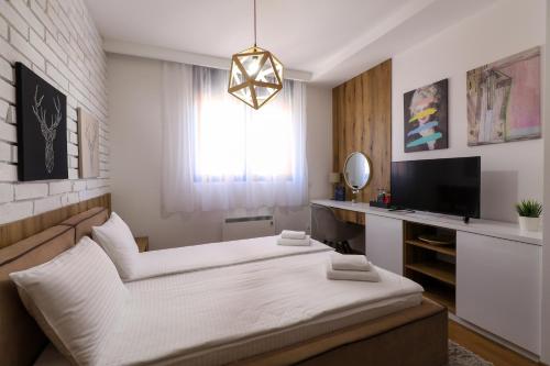 a bedroom with a bed and a desk with a television at All Seasons Residence in Zlatibor