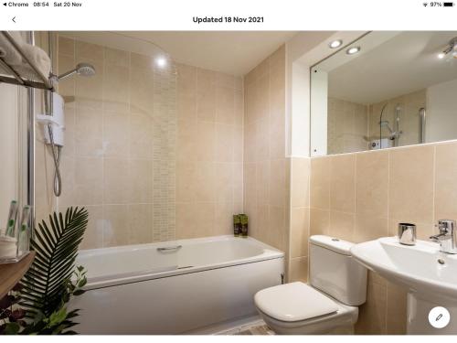a bathroom with a tub and a toilet and a sink at Stunning 2-Bed Apartment in Newton Abbot in Newton Abbot