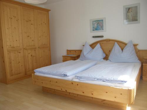 Schlafzimmer mit einem Holzbett mit weißer Bettwäsche in der Unterkunft Ferienwohnungen Kern in Weyregg