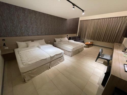 ein Hotelzimmer mit 2 Betten und einem Schreibtisch in der Unterkunft KLA B&B in Kaohsiung