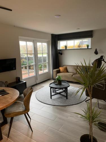 a living room with a couch and a table at Dijkhofje, dichtbij strand, zee en meer. in Vrouwenpolder