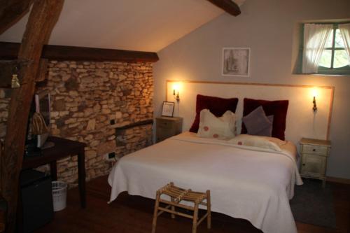 a bedroom with a large white bed and a stone wall at Domaine du Bouysset in Saint-Martin-le-Redon
