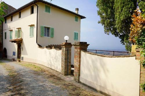 a white house with a fence next to a road at Antica Pietra holiday house with pool in Montaione