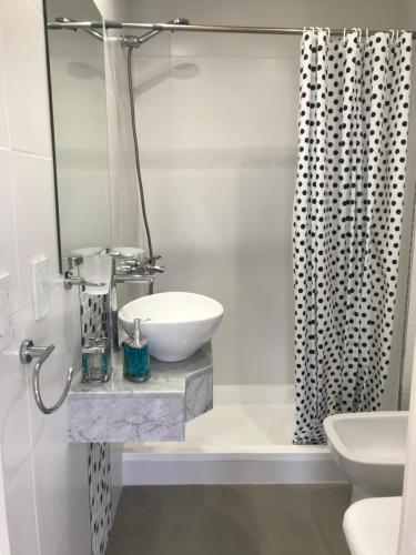 a white bathroom with a sink and a shower curtain at Departamento con Amenities in Pinamar