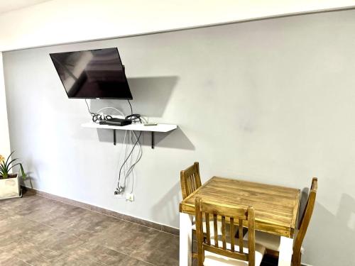 a dining room with a table and a television on a wall at Departamento Alassio in Tigre