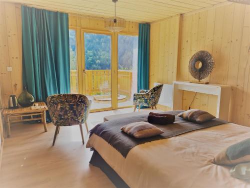 a bedroom with a large bed and a large window at Le Chalet Du Blanc Spa yoga in Aillon-le-Jeune