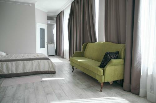 a bedroom with a green chair and a bed at Hotel Lux in Makhachkala