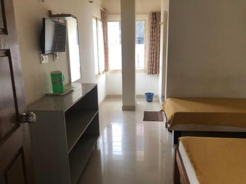 a room with two beds and a tv on the wall at Star Residency in Mysore